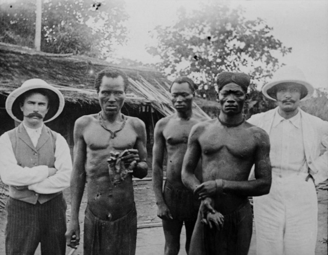 Alice seely harris  picture of bompenju  lofiko  a third person  john harris and edgar stannard with the hands of lingomo and bolengo  which have allegedly been killed by sentries of the abir  may 1904 